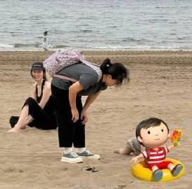 何穗带10个月宝宝在沙滩玩，穿黑吊带长裤配人字拖，很轻松很惬意