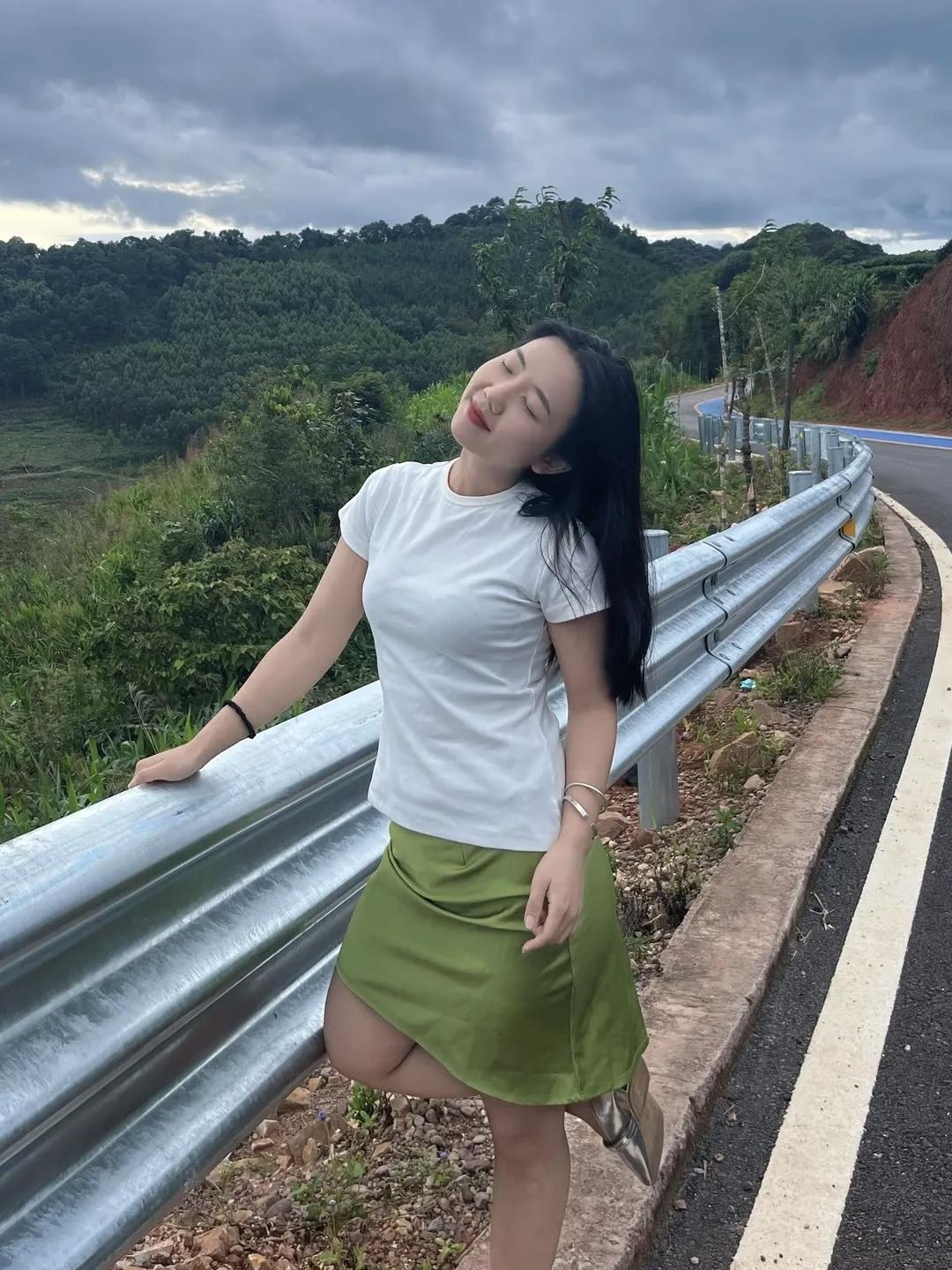 这姑娘在路边靠栏杆，风景真美。