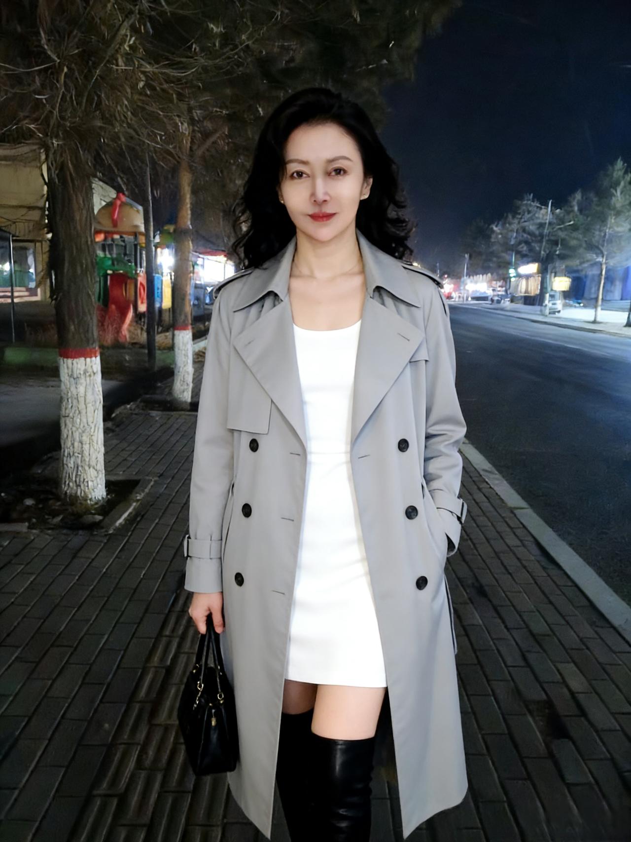 街灯摇影夜生寒，风衣轻裹玉容颜。白裙漫卷三分月，黑靴深踏一寸欢。持暖盏，倚阑