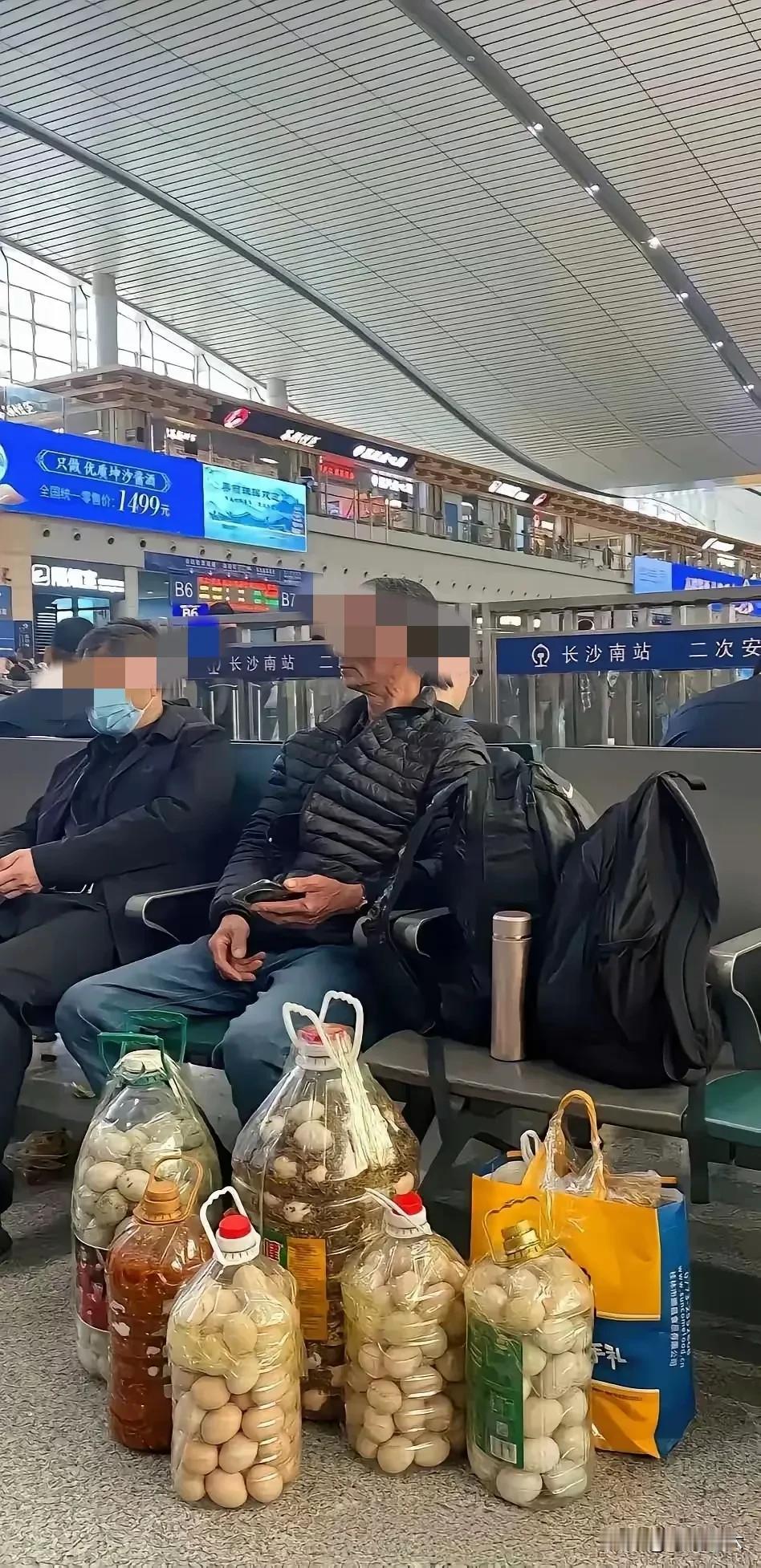 这应该是父亲对女儿的爱去看望坐月子的女儿，父亲用油桶装个几桶鸡蛋，坐在候车大厅