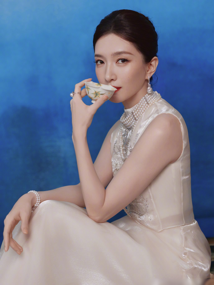 江疏影这组图，蓝底子，浅杏色裙子，手里捏着茶杯，眼神一点没往镜头外飘。评论区直接炸成两拨，一拨说美得