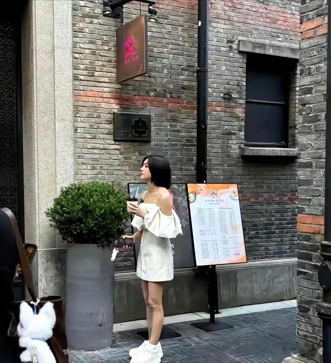 陈妍希上海被偶遇，白裙厚底鞋，真人瘦小只，娃娃脸淡妆很显嫩。白露肩裙轻盈，厚底小白鞋却笨重，审美小翻