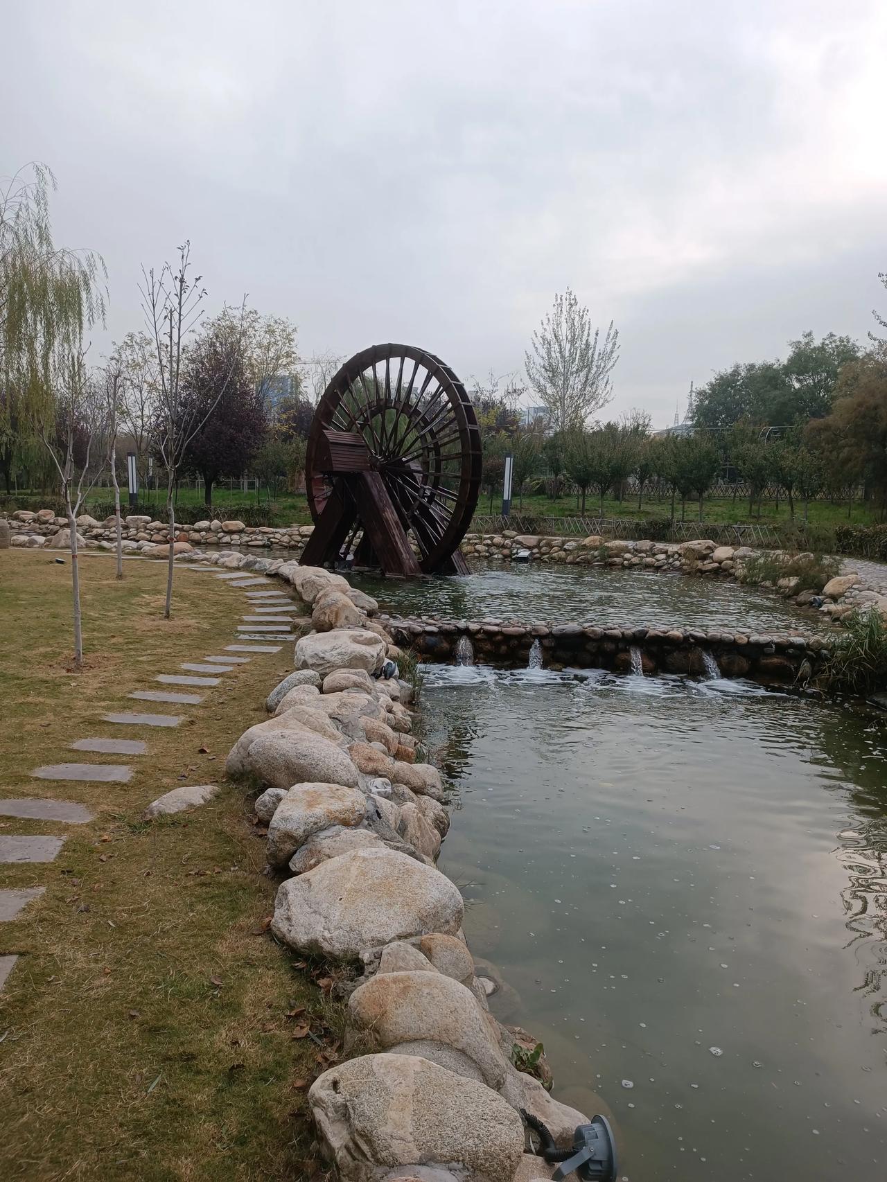 老水车倚着石溪轻晃，细流溅的碎光裹着浅冬的暖。枝头霜叶覆着柔调，风一吹晃出暖融