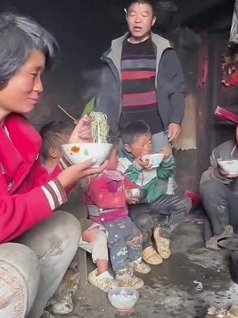3个孩子用手抓着吃饭，饭碗里没有一点菜，看起来吃的特别香，全家没有围在饭桌，只是