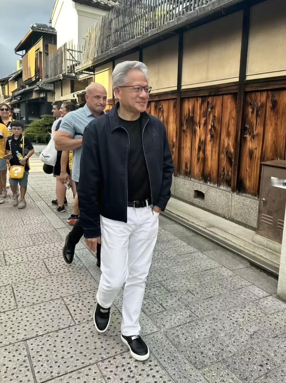 63岁英伟达总裁黄仁勋在日本京都街头被偶遇，大热天他还穿着皮衣，和旁边穿短袖的路