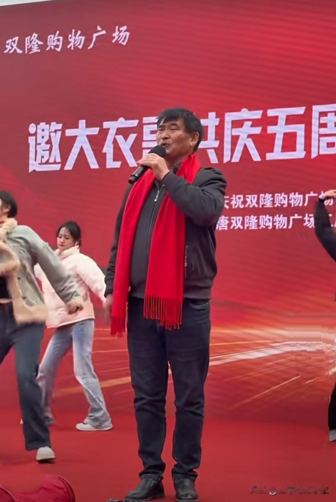 大衣哥朱之文挂着红围脖在聊城演出,大衣哥朱之文越来越时尚了,皮鞋牛仔裤,时尚夹克