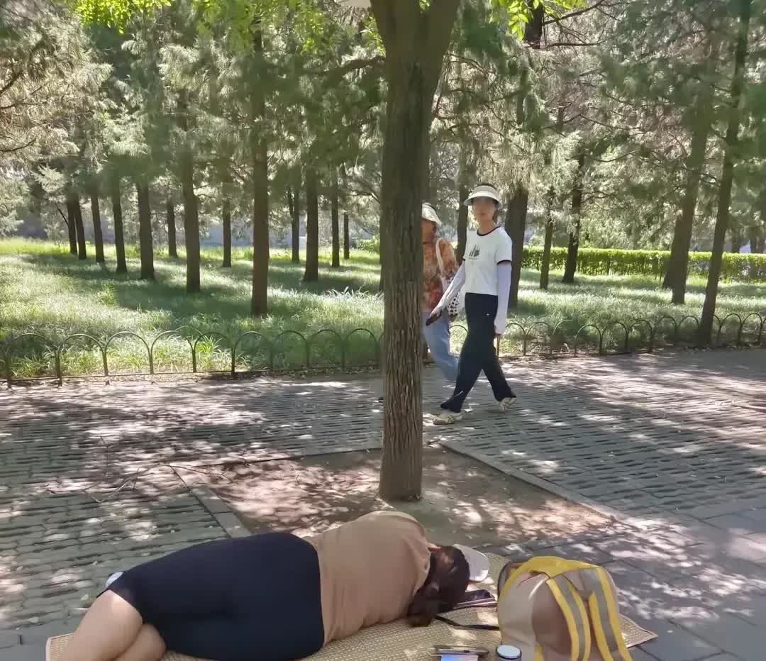 北京，在天坛公园里，有很多市民到公园游玩期间，发现一名年轻的女子躺在公园的树荫下