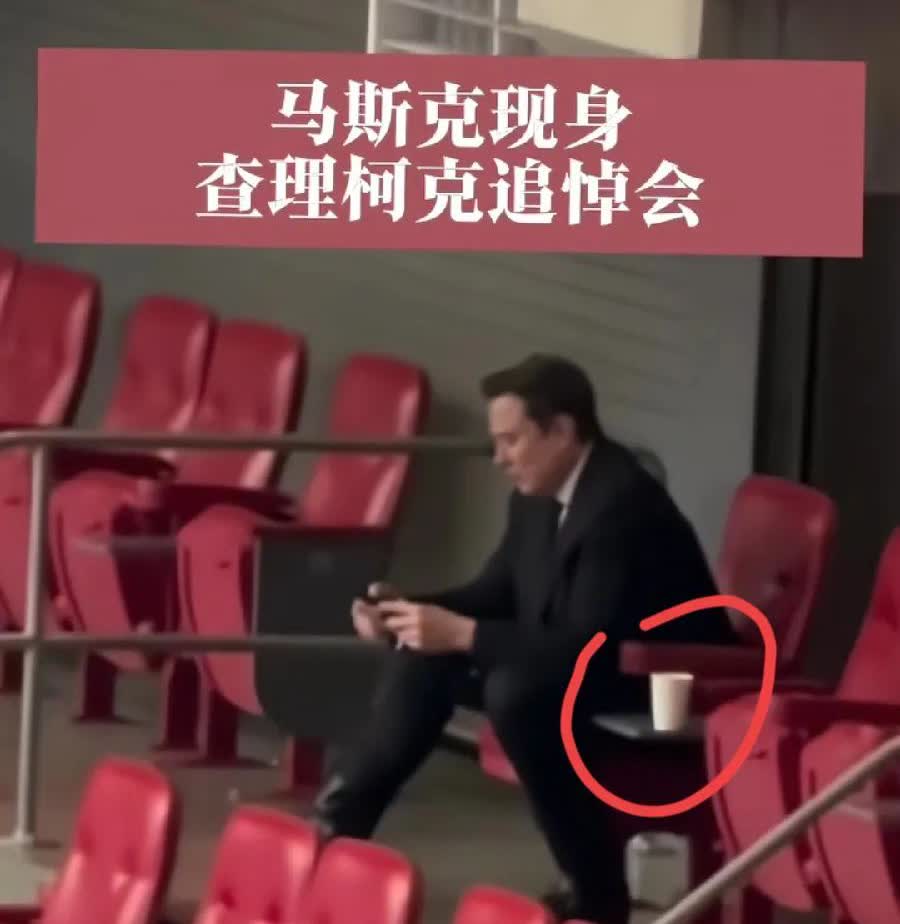 马斯克一个人坐在角落，手里攥着纸杯水，手机屏幕亮着没停。五千人喊着口号，他没