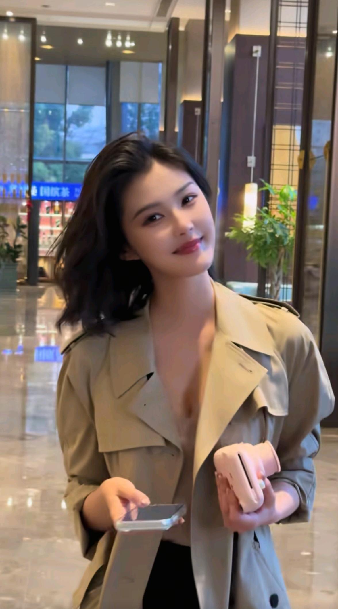 都市时尚女孩，手拿手机和粉色小包，微笑面对镜头。