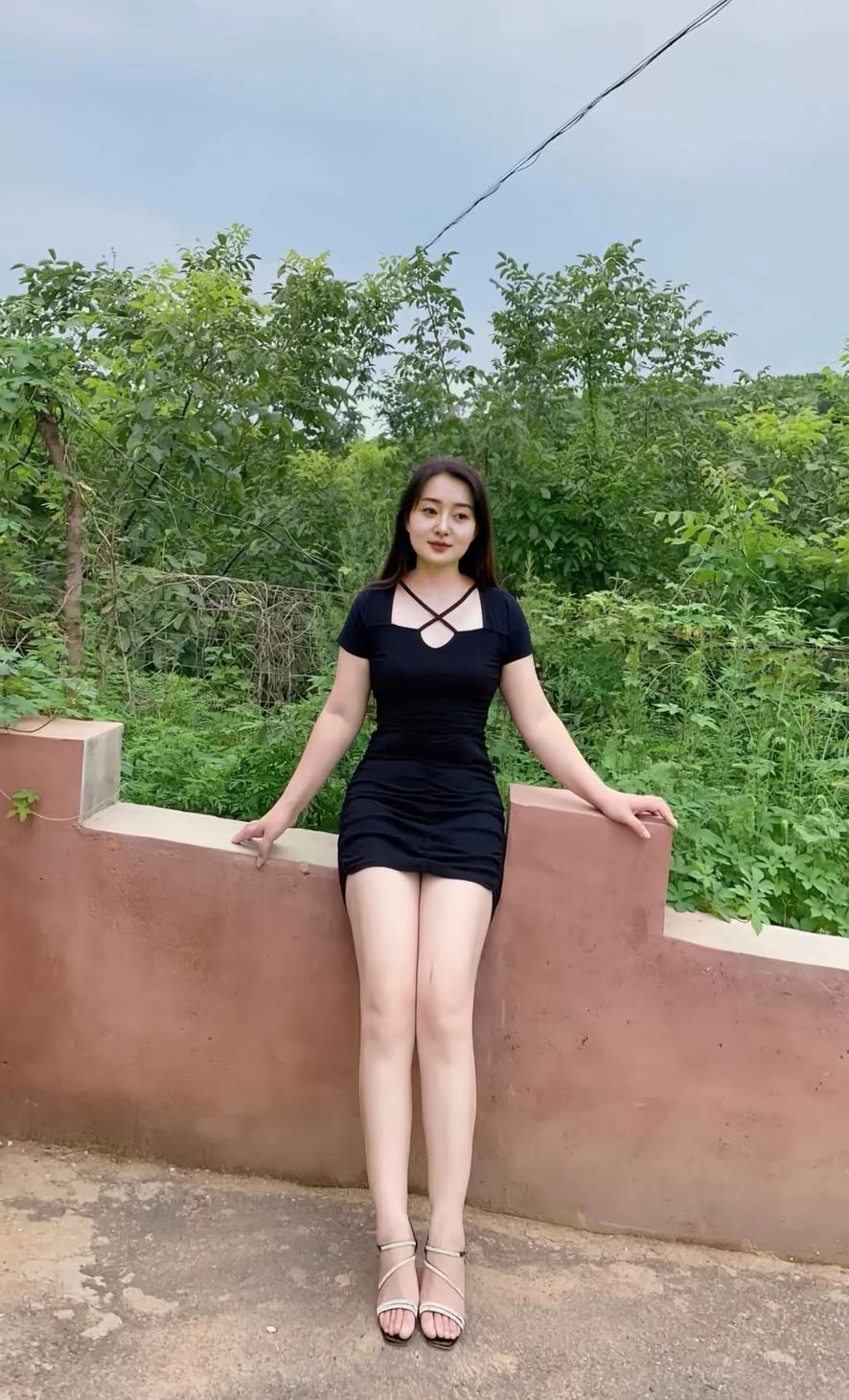 夏日绿意中，黑裙美少女，静坐墙边，享受自然。