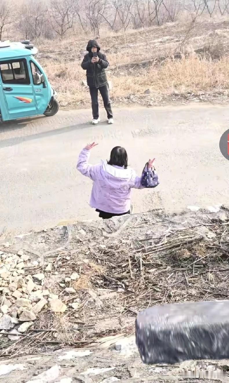 姐妹俩在山脚下的路边拍照，突然一块石头从山坡上滚落下来。流浪狗听到动静，赶忙起身