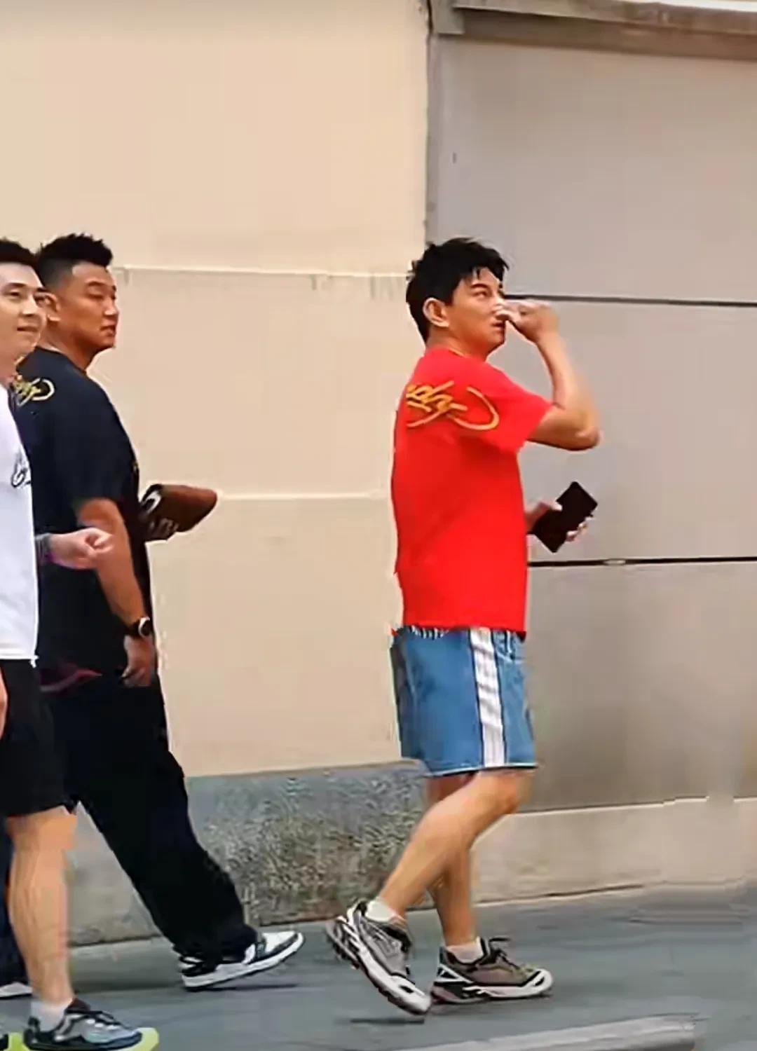吴奇隆在上海街头游玩，依着随意，一件红色体恤衫陪蓝色短裤脚上一双灰色运动鞋，小腹