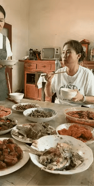 一家人正在吃饭，儿媳妇又做了一个菜，刚端到桌子前，还没有把菜放桌子上，婆婆就慌着