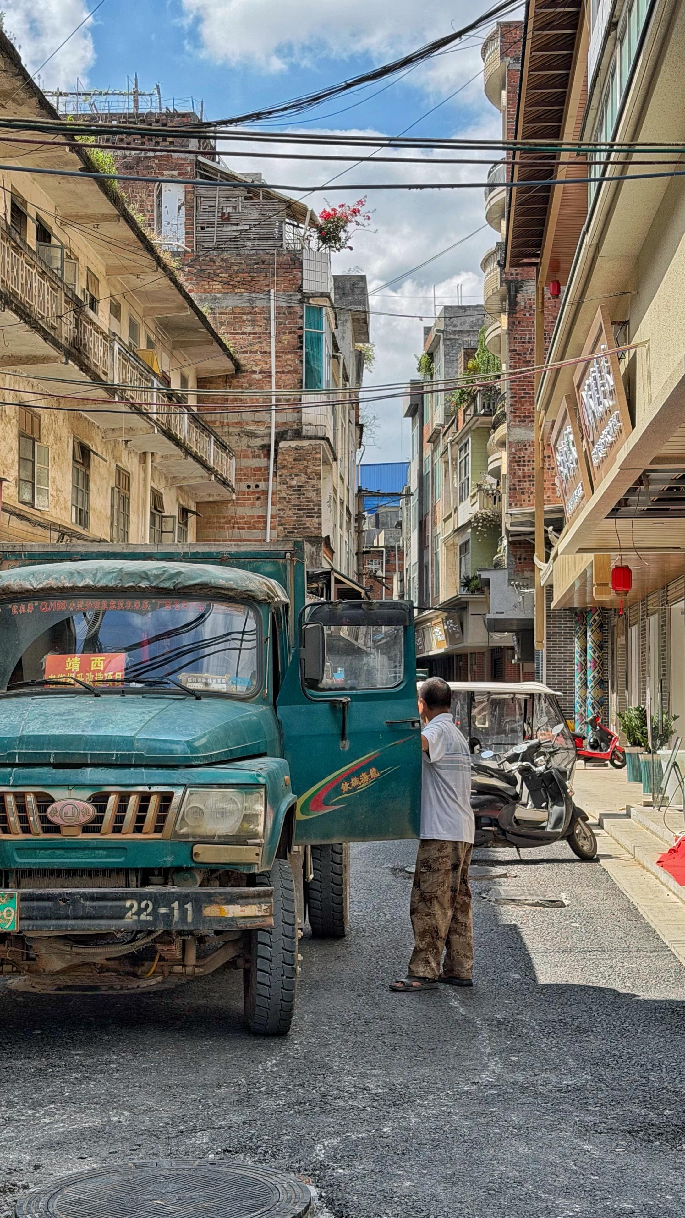 在靖西城中村的街巷里，老货车、摩托、当地老人与烟火相融，壮绣针线间，越盟靖西办事