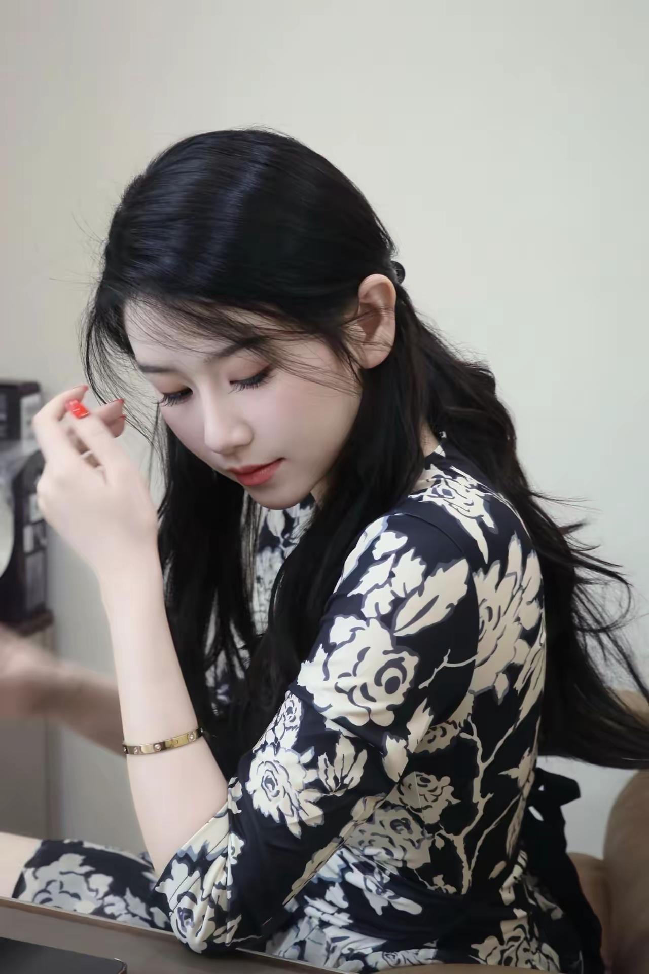 温柔黑发少女，精致妆容，花裙飘逸，低眉浅笑，优雅动人。简单的穿搭风格，掩饰不住的