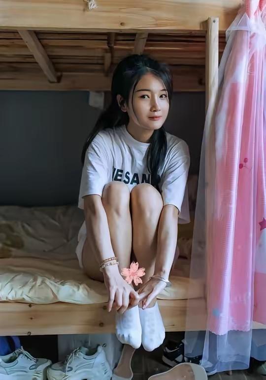 妹子在宿舍里坐着，脚丫子翘起来。