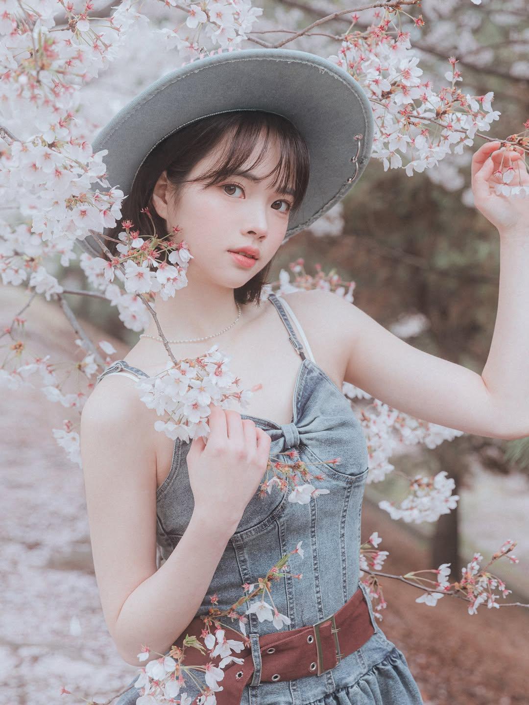 樱花树下，少女轻抚花枝，春意盎然。