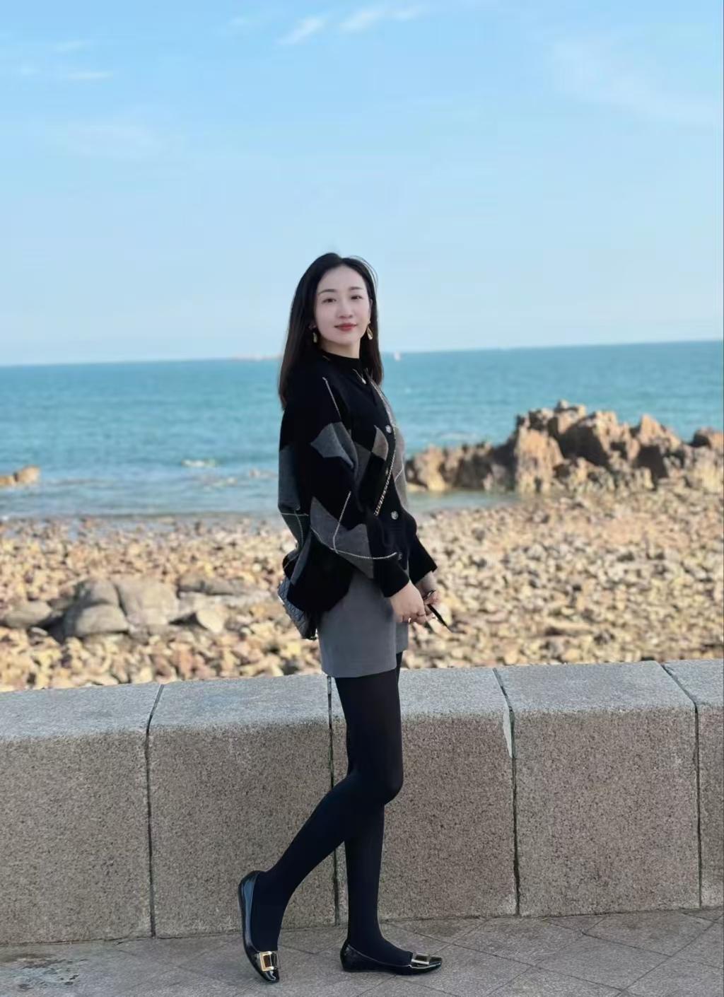 秋日的海边，天空澄澈，白云悠悠。我穿着黑色丝袜与平底鞋，在岸边拍照留念。