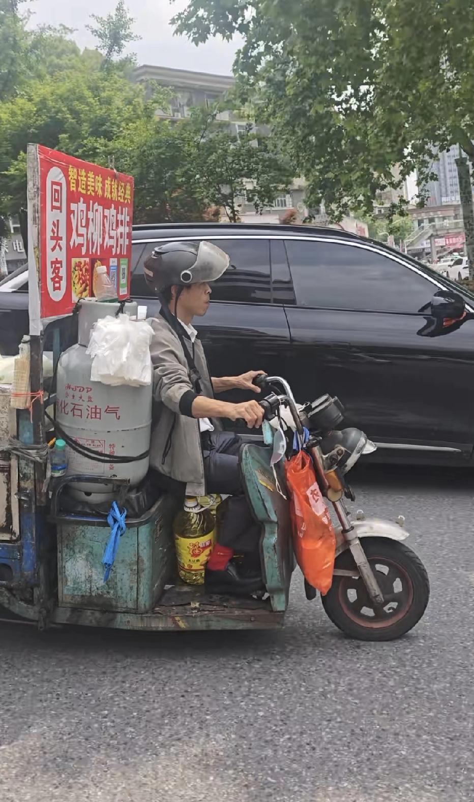 可是，再看看他的摆摊车，真的是一言难尽啊。这辆三轮车，都被开出了包浆感了，车体脏