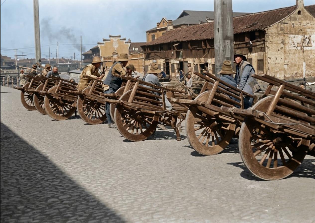 1917年，南京街头，石板路旁，一排木制独轮车（俗称“鸡公车”）整齐停放，大木轮