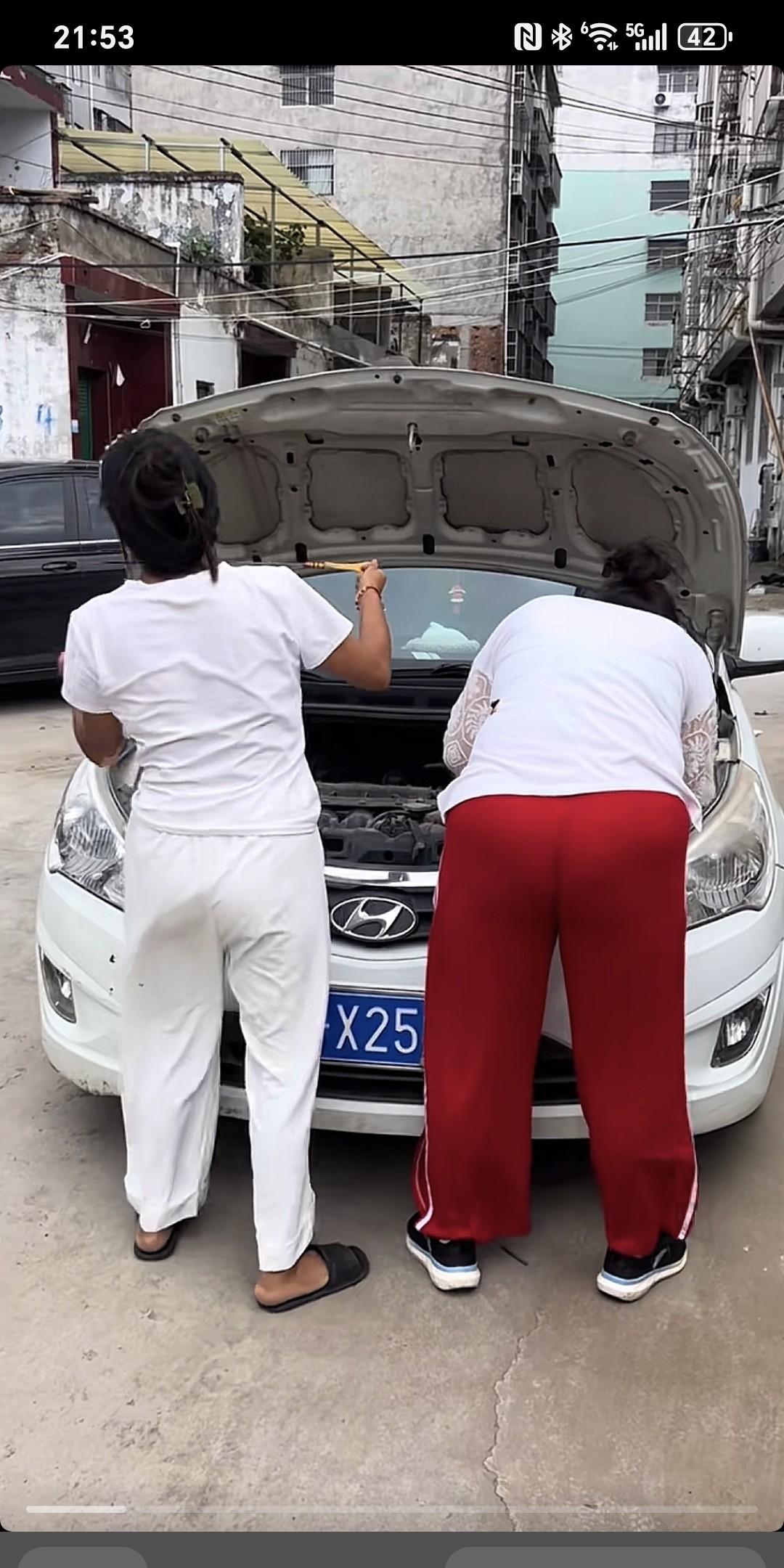 女子结车量机油，抽出机油尺，想擦了一下，但手中一时找不到顺手东西擦，只见她灵机一