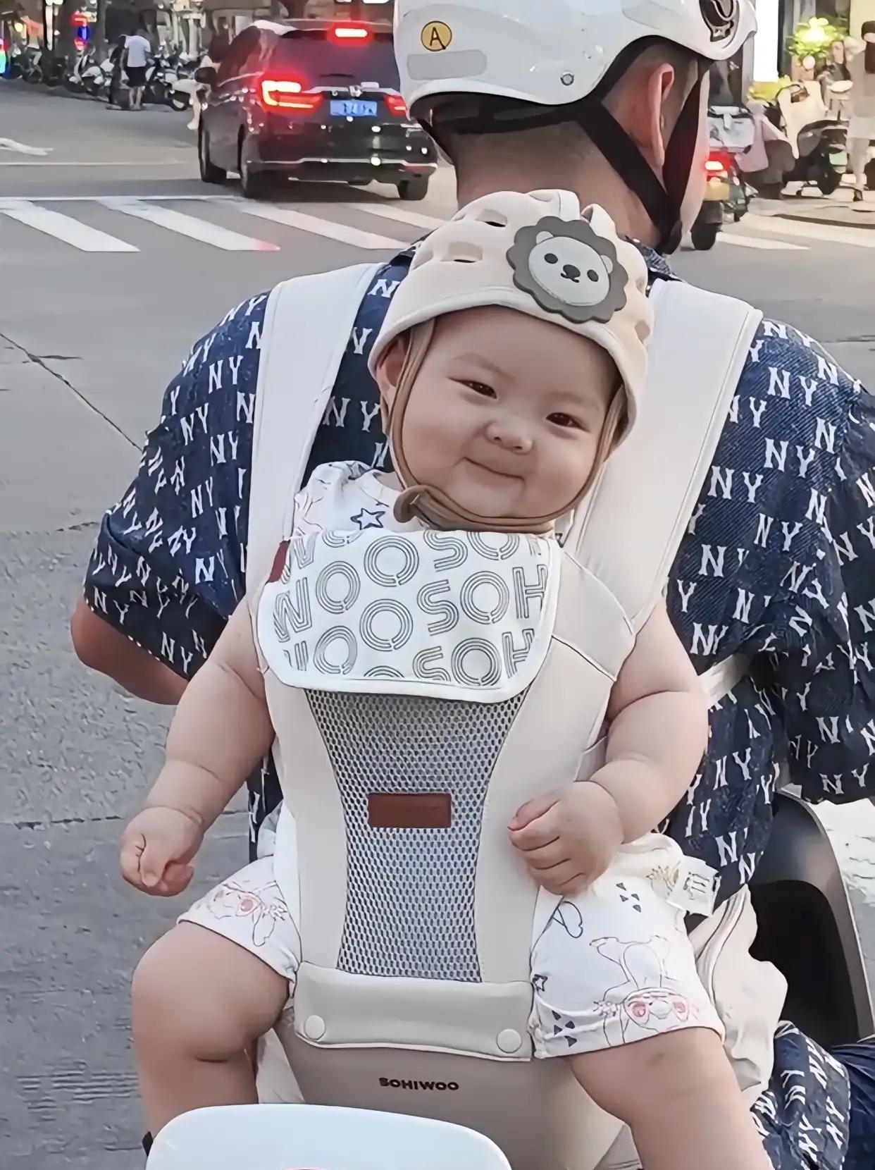 好喜庆的小宝贝，笑容也太治愈了！一男子骑着电动车后背上背了一个小娃娃，小娃娃胖乎
