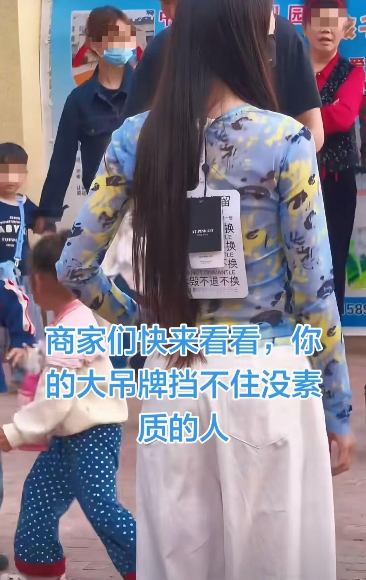 一所小学门口，家长乌泱泱一大片。有个网友眼尖，发现前面一个女的，后背上挂着个东西