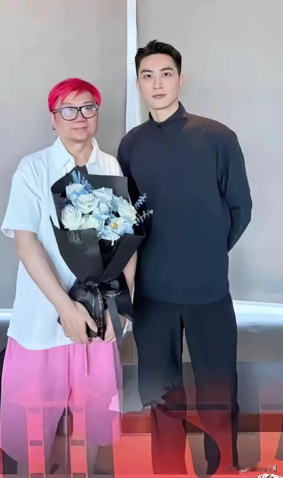 猛一看，是一男一女的合影。其实是两个男人的合影。抱鲜花的是个不折不扣的男人。