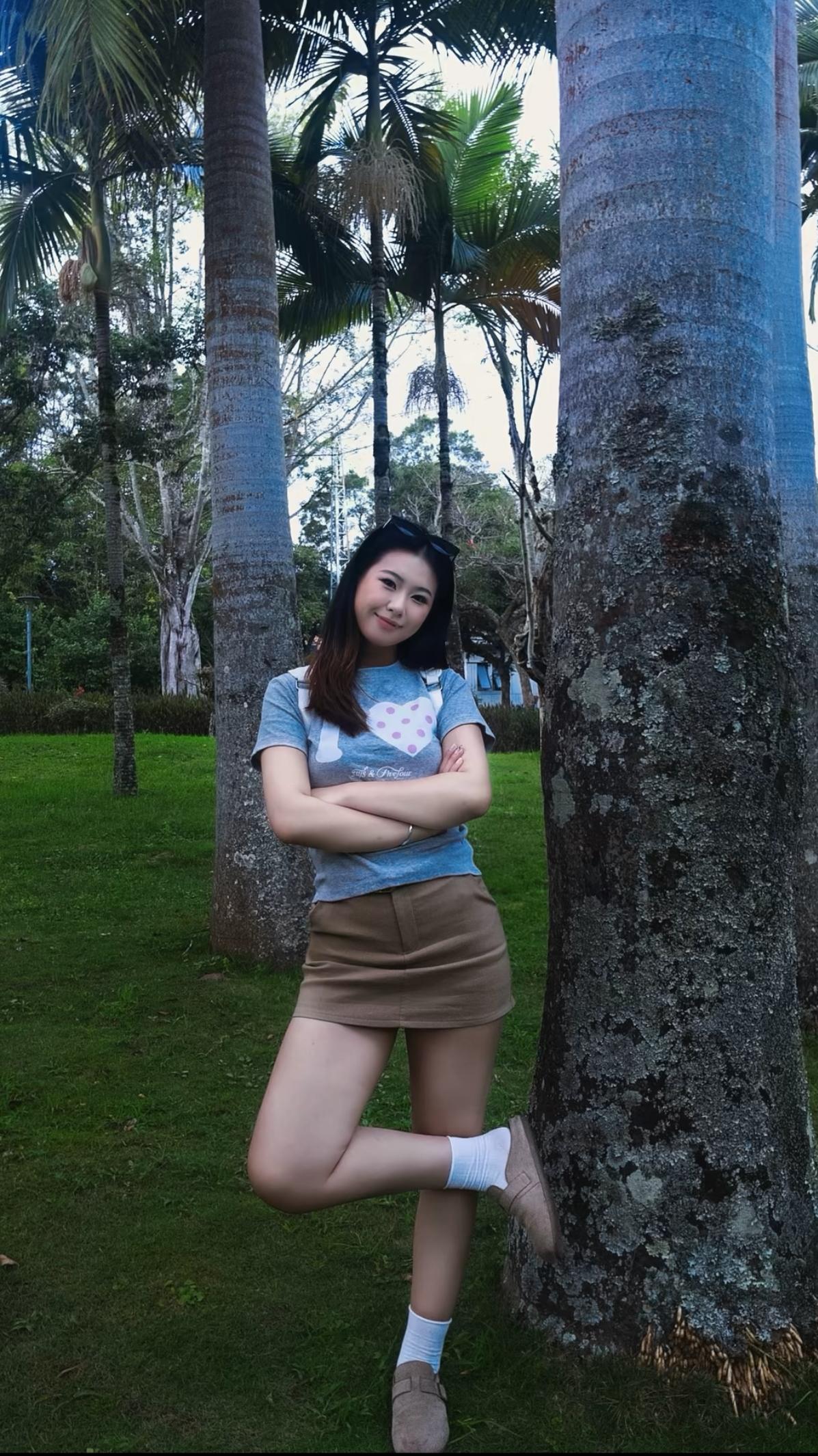 这姑娘在公园靠树摆姿势呢。