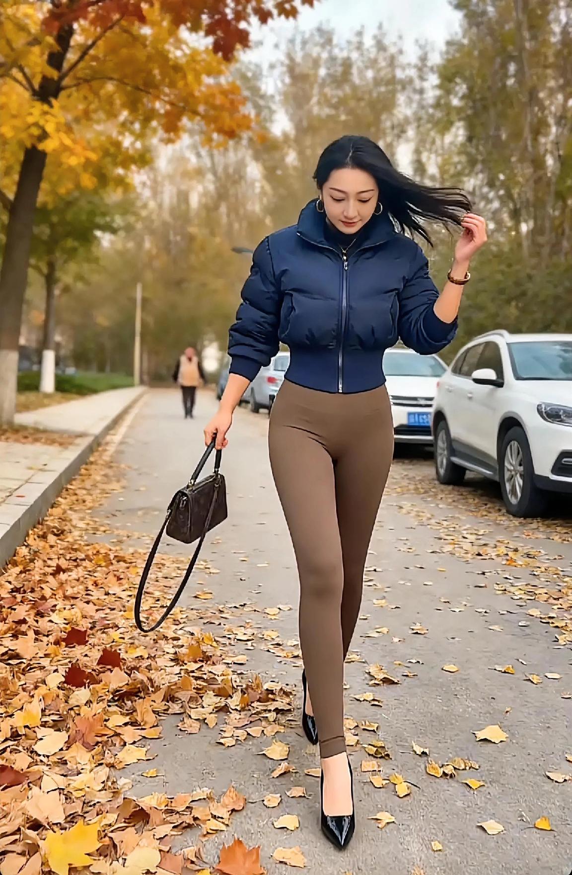 美女在秋天的小路上走着。