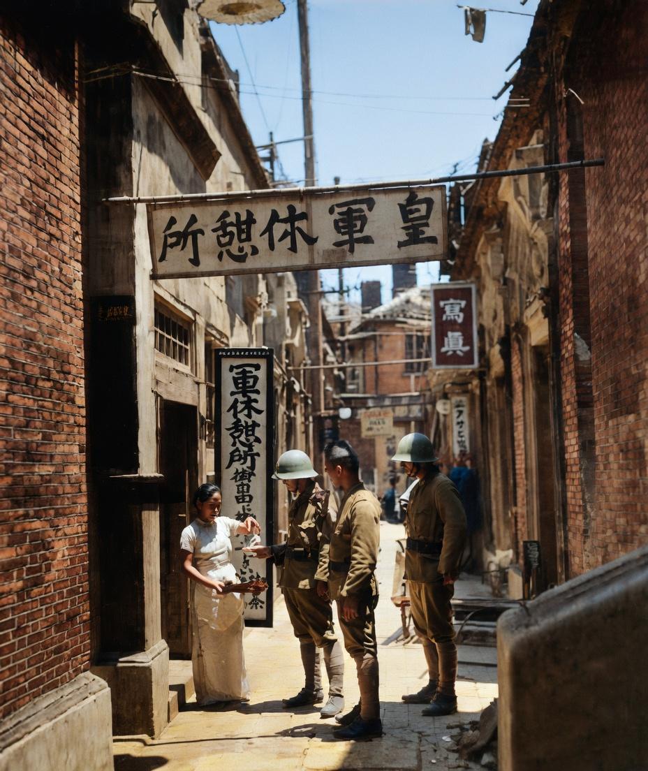 1937年，上海沦陷区，石库门里弄，三名日军士兵站在门口，一名受害女性在旁等候。