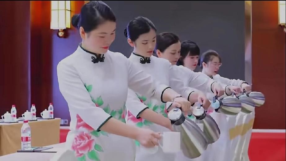 统一穿着白色的旗袍，旗袍上还绣着国花牡丹，都是年轻漂亮的面孔，看起来着实赏心悦目