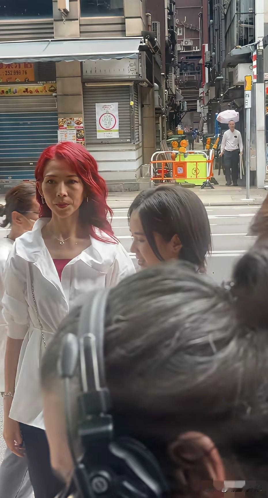 52岁的蔡少芬真的不服老啊！顶着一头鲜红的长发在街头拍戏，身材依旧苗条，唯一美