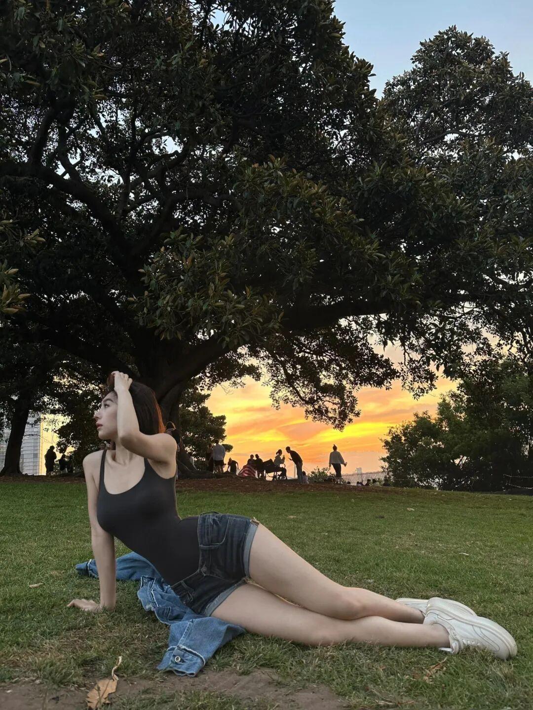 夕阳下的公园，少女轻倚树旁，静享美好时光。美少女穿搭高雅气质美女今日份元气