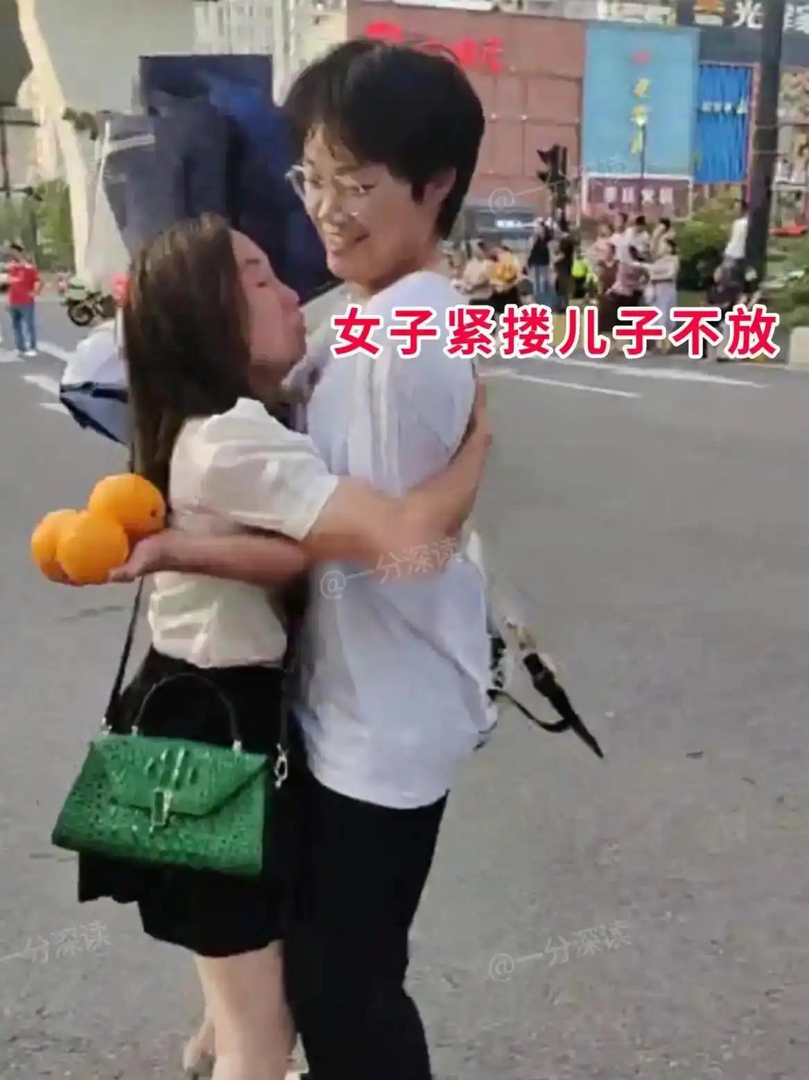 街头人来人往，妈妈见到许久未见的儿子，激动地上前紧紧抱住，还凑过去亲吻。可已经长