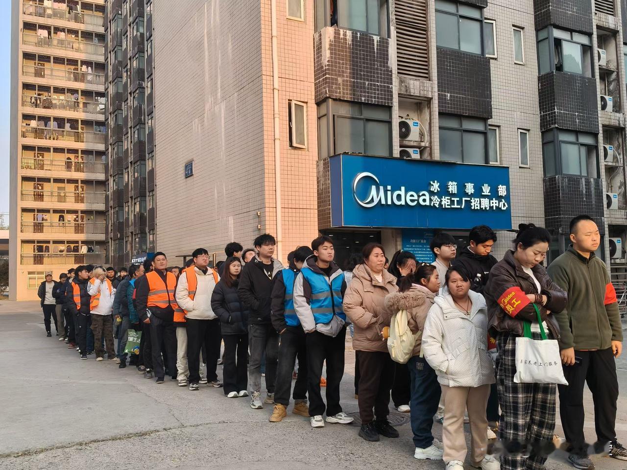 Midea冷柜工厂招聘中心外排起的长队，着实壮观！大家都眼巴巴盼着进厂工作。美的