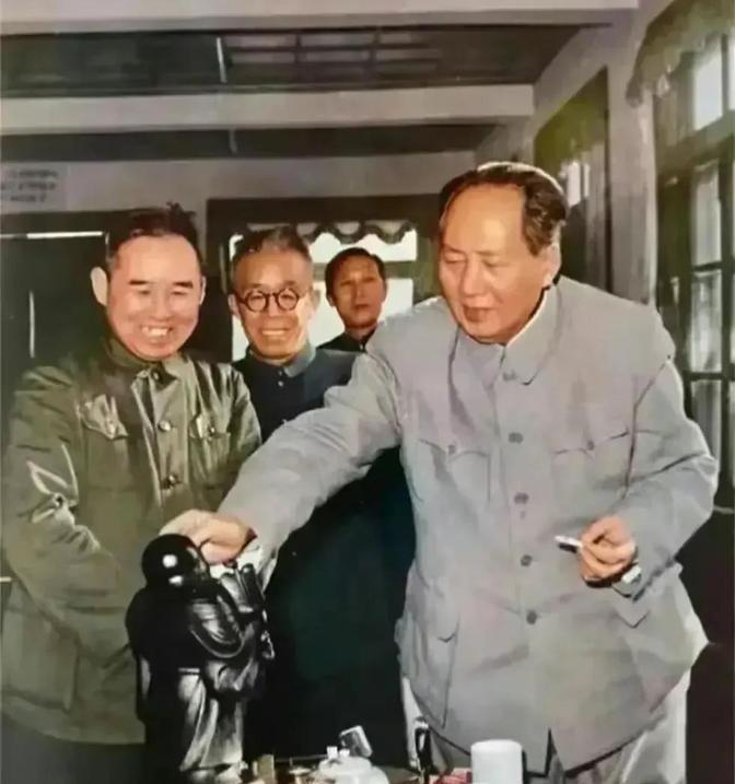 毛主席一只手吸着烟，另一只手摸着弥勒佛像幽默风趣地说，佛兄啊，你头大，肚子也大，