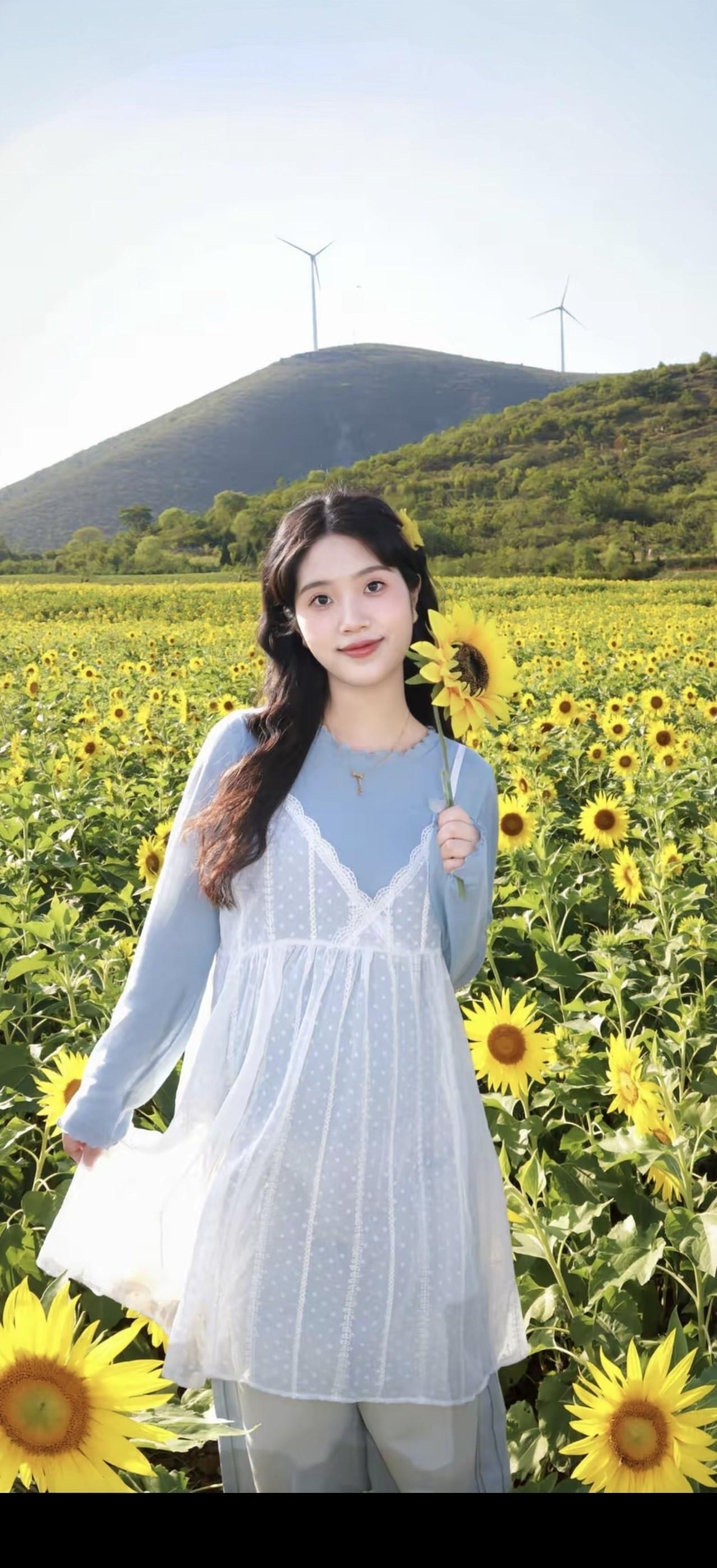 一个女孩在向日葵田里拿着花。