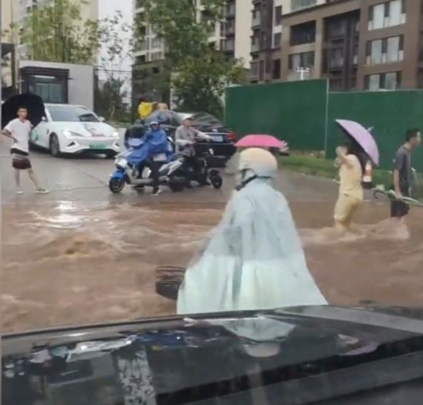 近日在山东，一场暴雨过后，路面低洼的地方被水淹没，虽然水不深，但是流速很快，一名