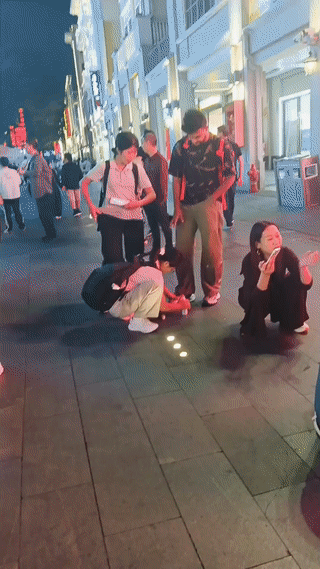街头拍到的奇葩一幕！两名年轻女子一个蹲下来给外国友人系鞋带？另一个则递过来手