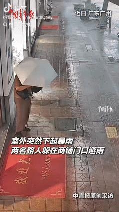 都是讲究人！广东广州，2大妈在外闲逛时，突然下起了暴雨，2人只好躲在商铺门口避雨