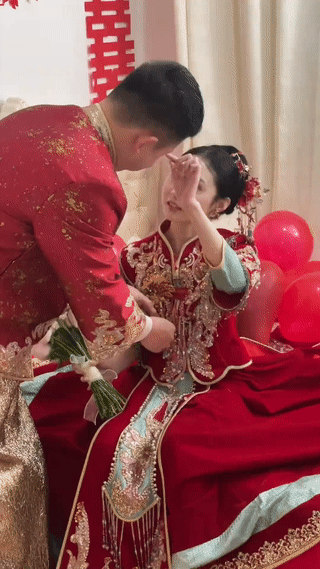 婚礼现场，新郎正在为新娘整理衣服。而新娘则十分深情的抬头望着新郎？真是幸福满