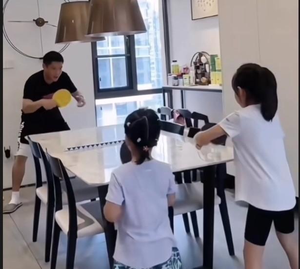 女儿奴co爹在家陪小豌豆打女双。coco在家里的客厅的餐桌上放个隔离条，父女二人