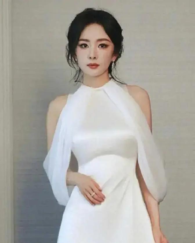 杨幂最近现身活动，一件白色长裙直接把全场目光都抢走了！这裙子剪裁超聪明，领口微微