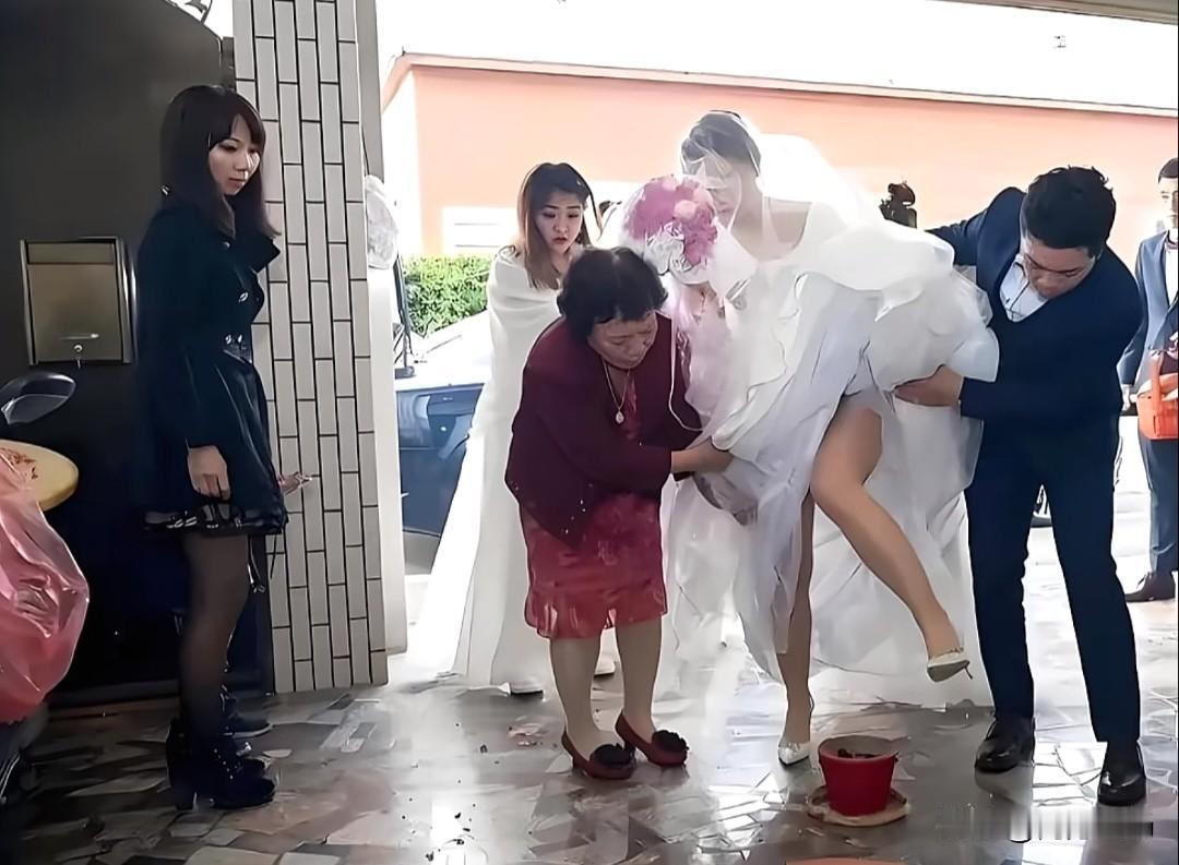 新娘撩开婚纱跨火盆，寓意红红火火！看到一张婚礼现场图，新娘正小心翼翼地跨过一个火