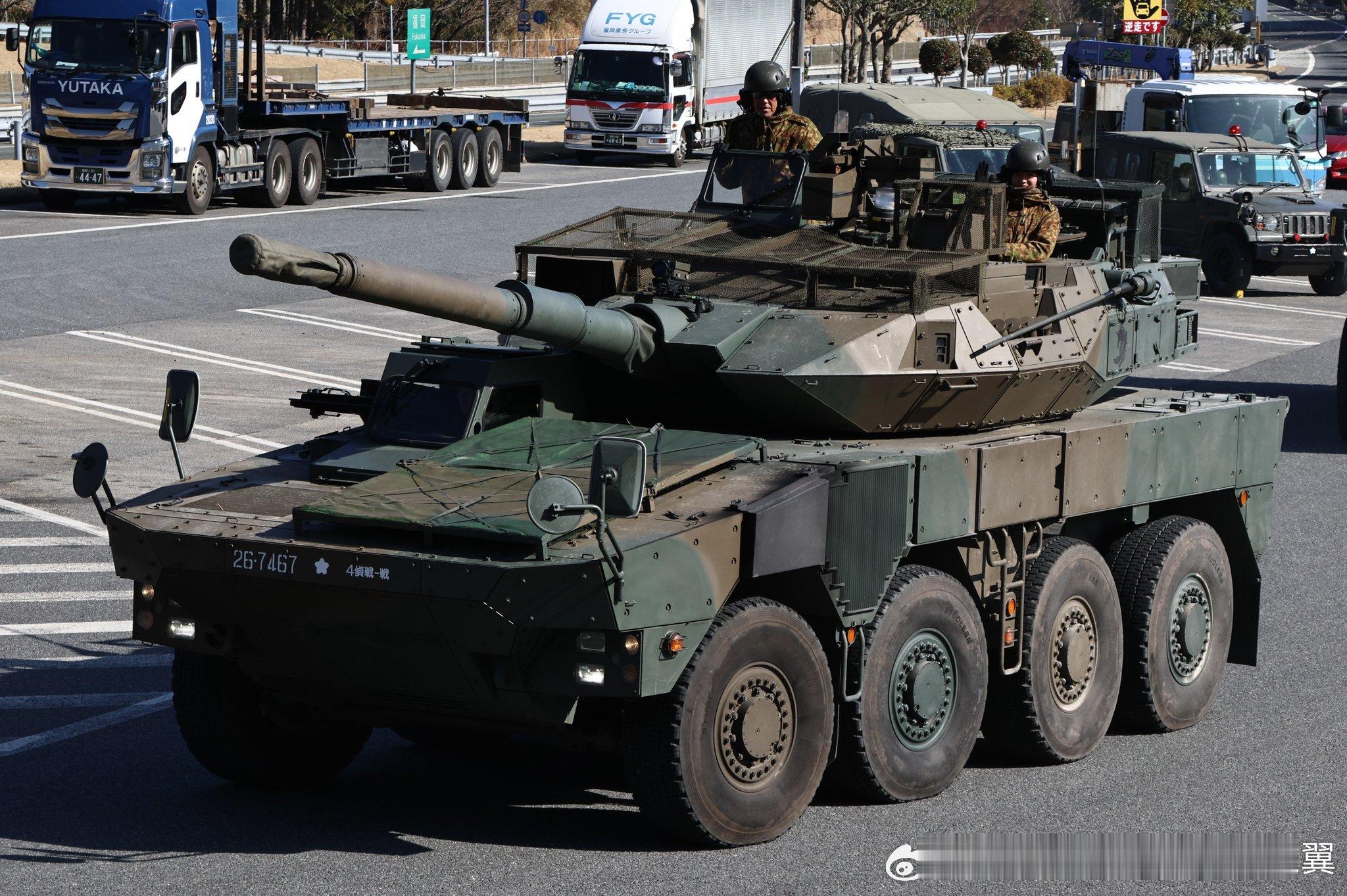 日本16式轮式战车安装无人机防护装置，包括炮塔顶部的笼子和发动机区域的护板。