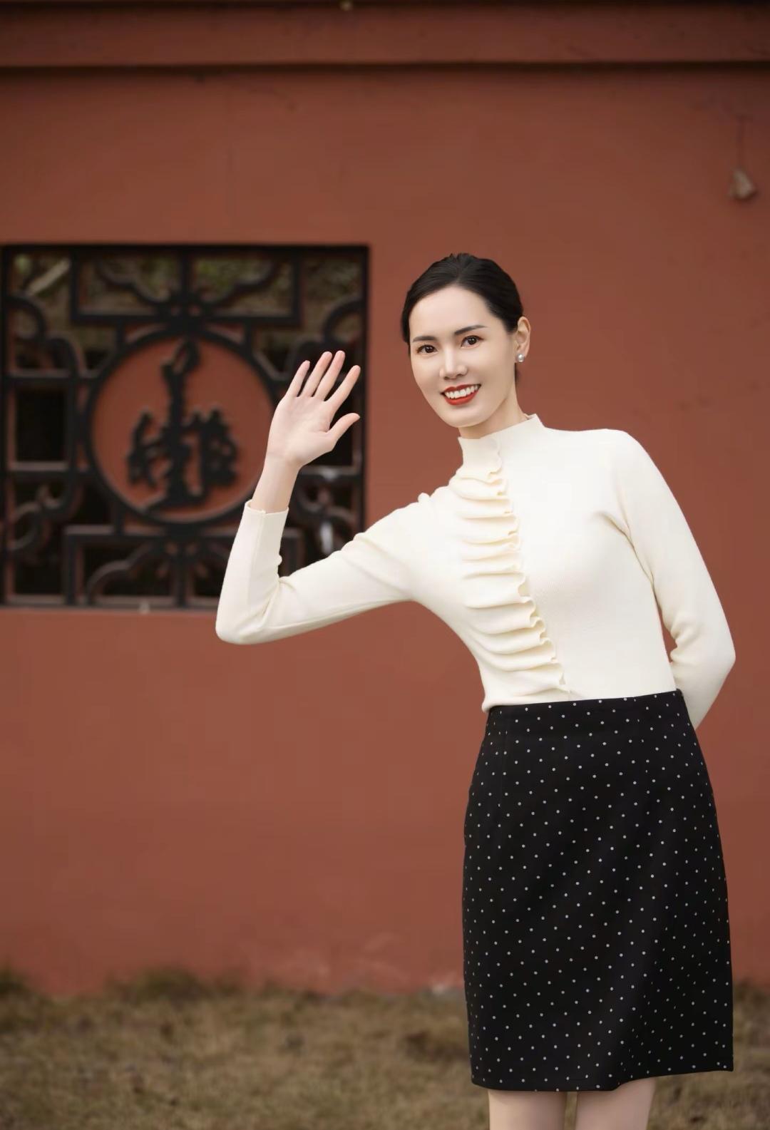 这位女士穿着时尚，在微笑打招呼。