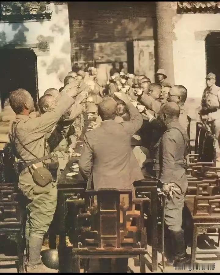 这么多日本鬼子围在桌子前，手里好像是举着酒杯，嘴里好像还在嚷嚷着什么，这应该是在