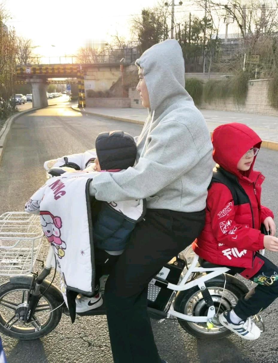 梁靖崑居然骑电动车，而且还有挡风被。两个儿子一前一后，像极了接俩娃放学的家