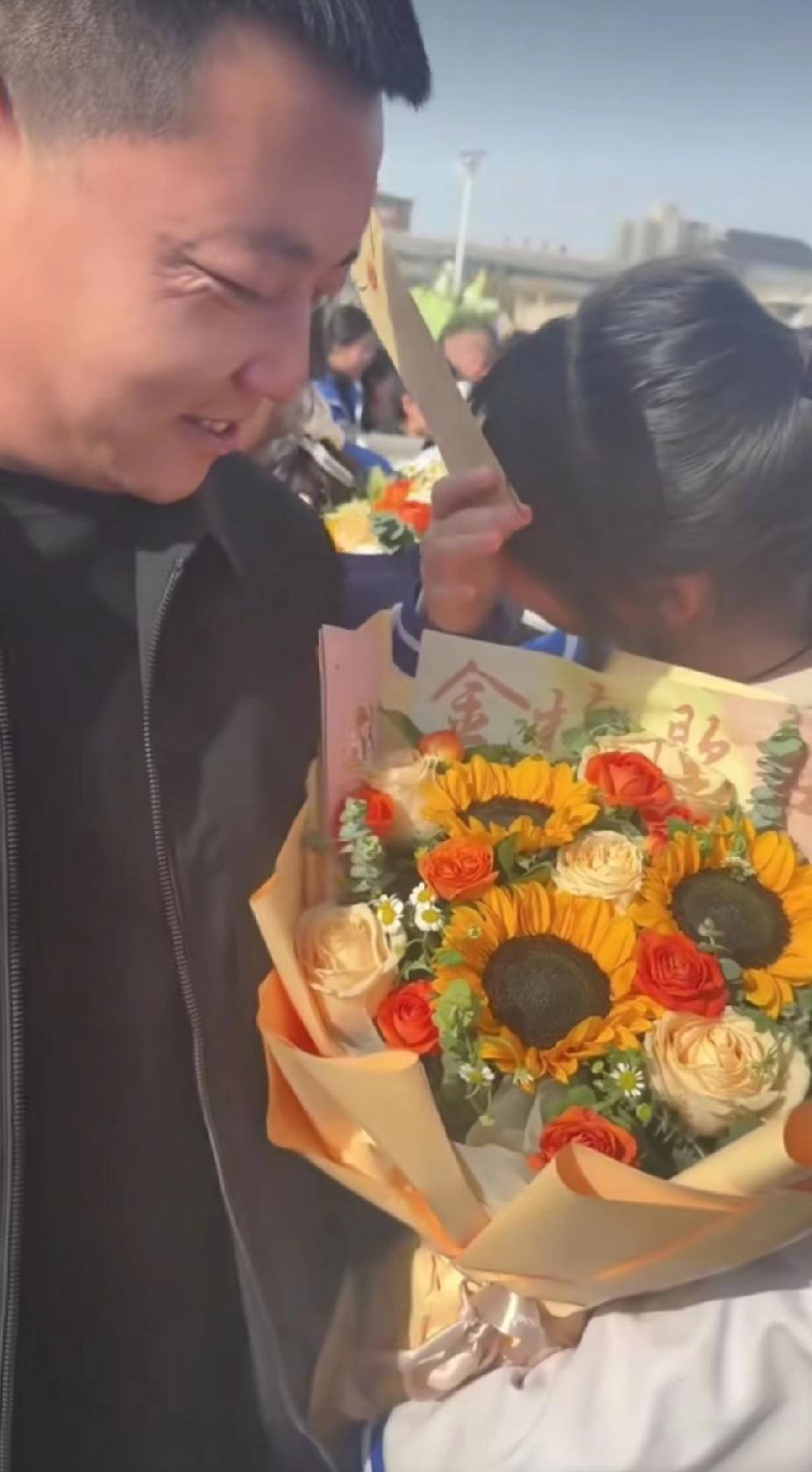 学校的高考百日誓师大会现场，一名男子突然抱着鲜花，出现在一个女孩眼前，让女孩瞬间